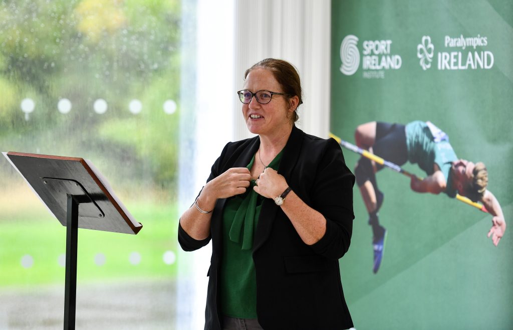 Neasa Russell speaking at a lectern in front of a Paralympics Ireland banner.