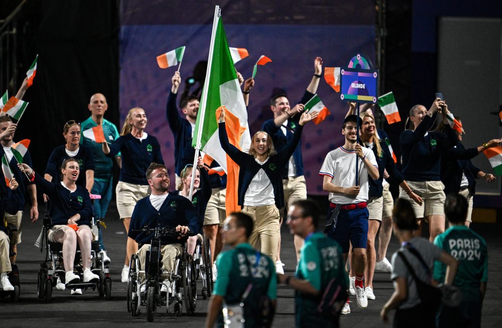 Orla Comerford (right) and Colin Judge lead the Irish team through the stadium, waving tricolour flags as teammates cheer and celebrate around them during the Paris 2024 Paralympic Games opening ceremony.