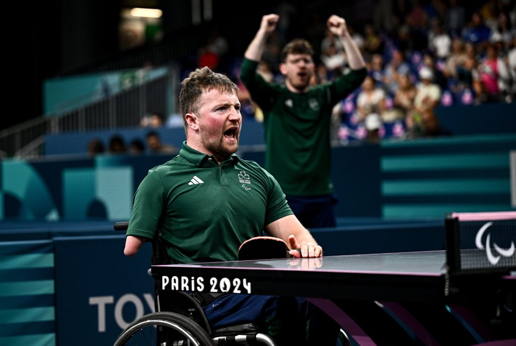 Colin Judge of Ireland celebrates winning a point during his men’s singles MS3 match at the Paris 2024 Paralympic Games, with coach Sam Logue raising his arms in the background.