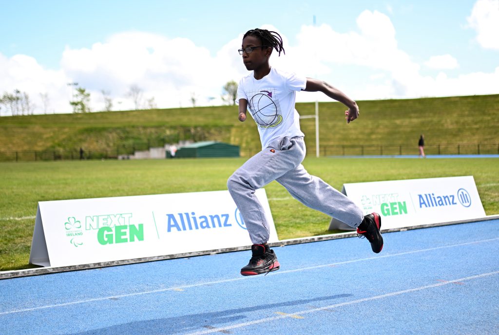 A young athlete running on a blue outdoor athletics track