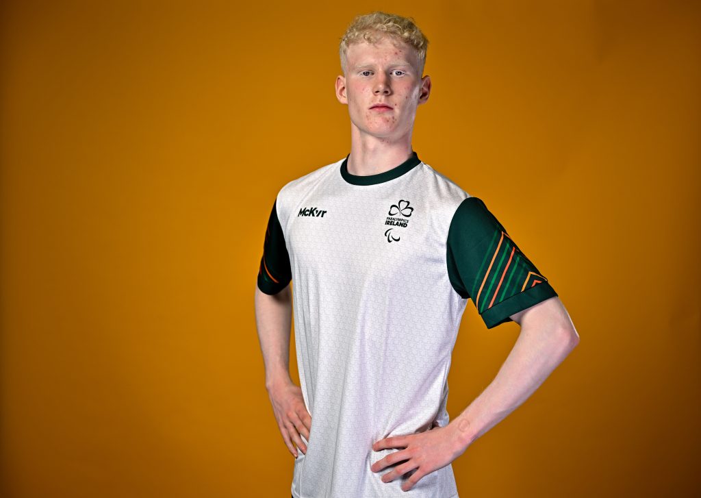 Damien Moyles, Para Athletics, poses for portrait during the European Youth Games 2025 Team Photo Shoot at the Sport Ireland Institute on the Sport Ireland Campus, Dublin. Orange background hands on hips looking serious