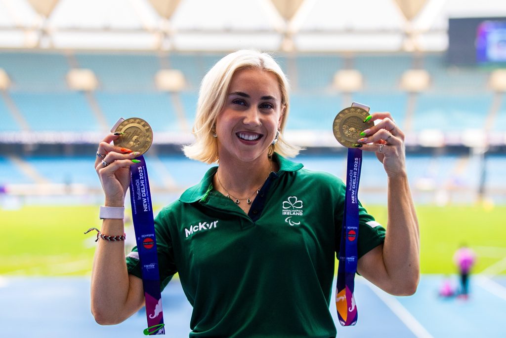 Orla Comerford smiling holding a gold medal in each hand