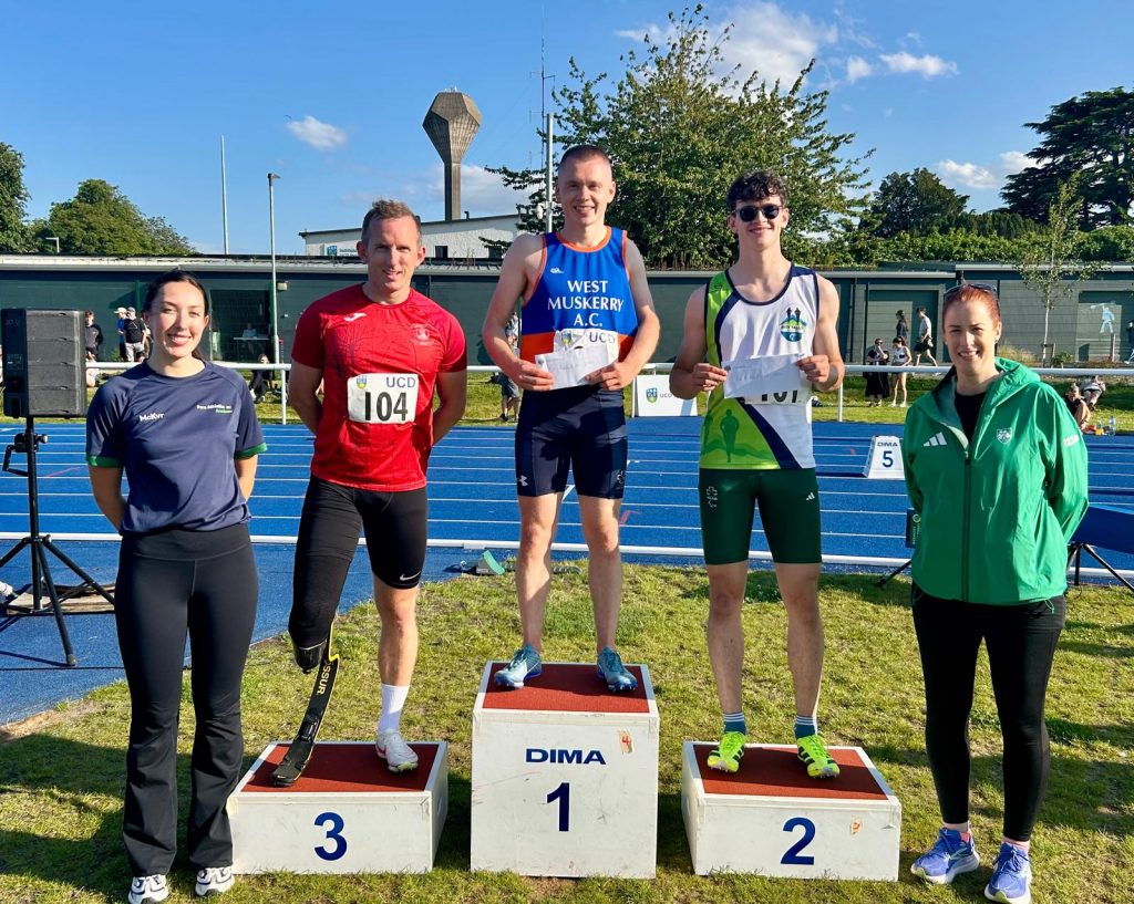 Alex Lee (left) stands in third place, Cathal Ryan (centre) stands on the top step, and Fíonan Ruane (right) stands in second place on the podium after the men’s ambulant 100m at the UCD Inclusive Meet.