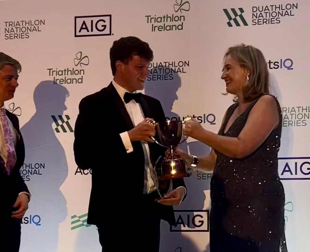 Lisa Clancy smiling presenting the Para Triathlete of the Year trophy to Tom Williamson